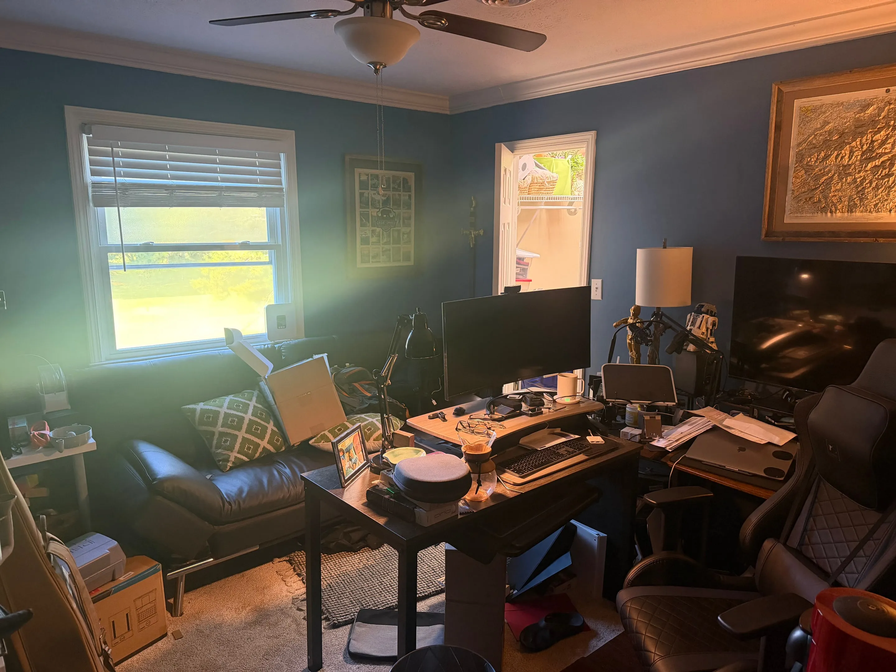 Room with blue walls, a ceiling fan, a desk, and a window.
