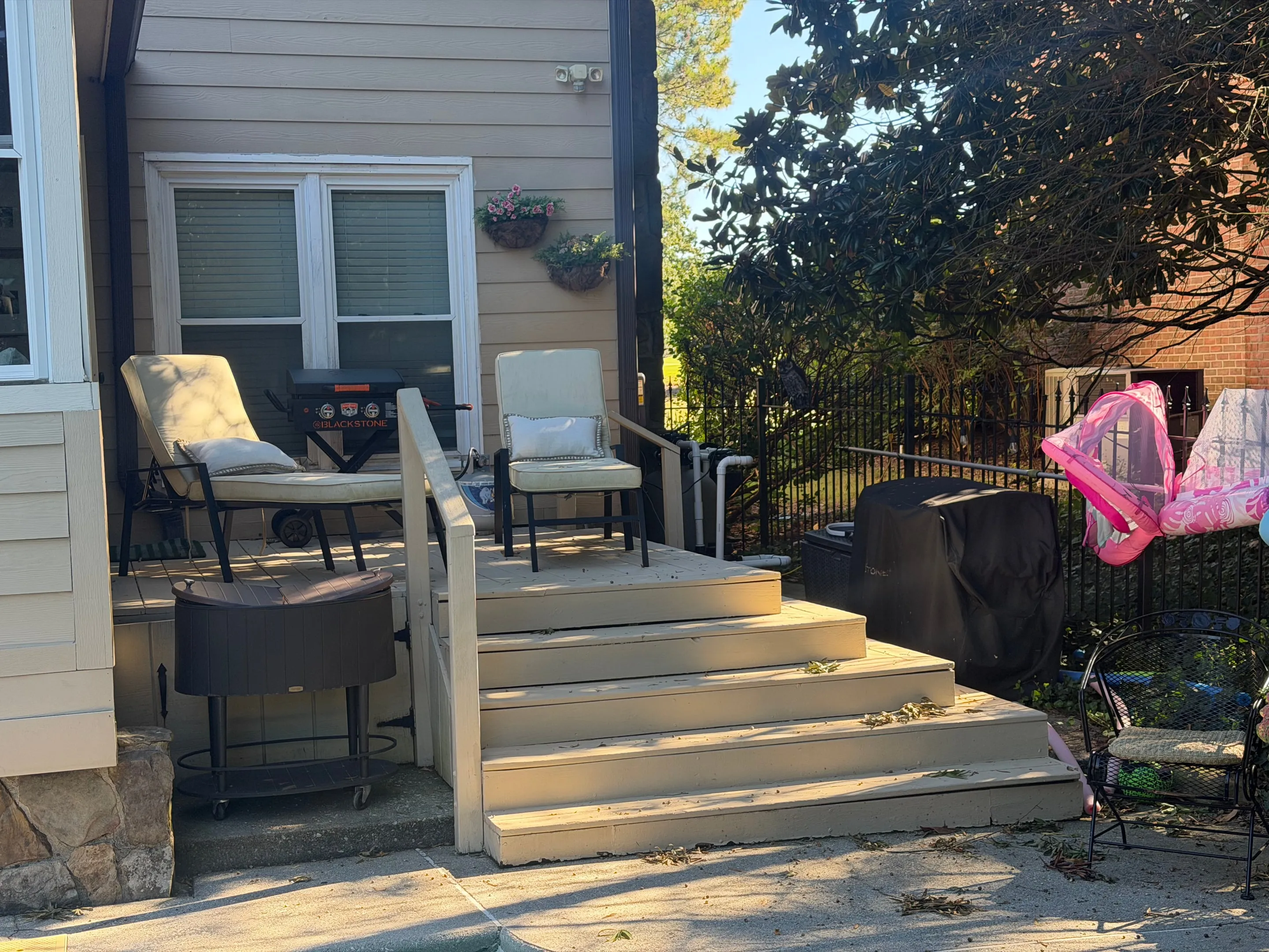 Wooden deck with two cushioned chairs and wide steps down to the patio.
