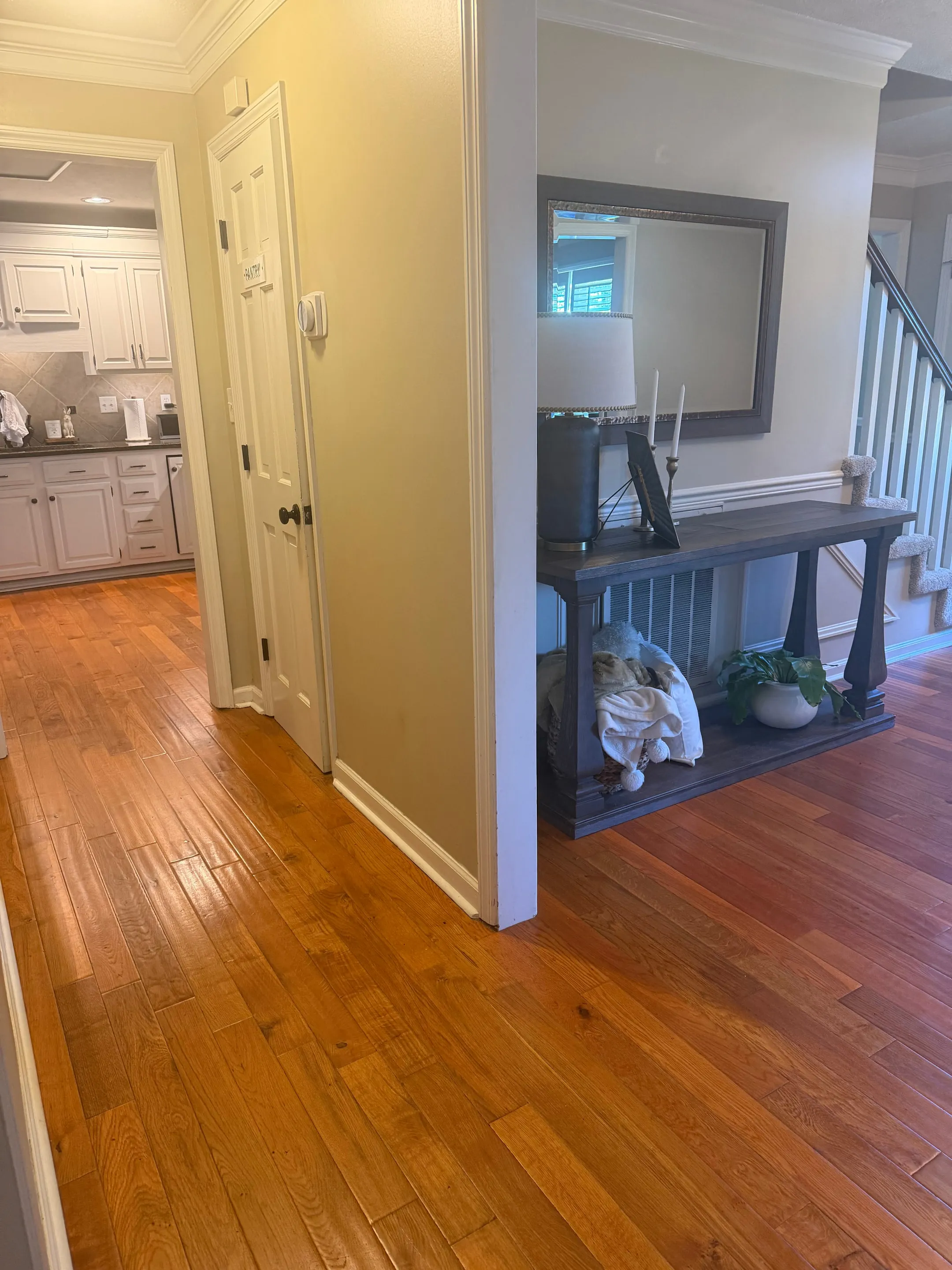 Hardwood hallway from the foyer with the kitchen visible at the end.