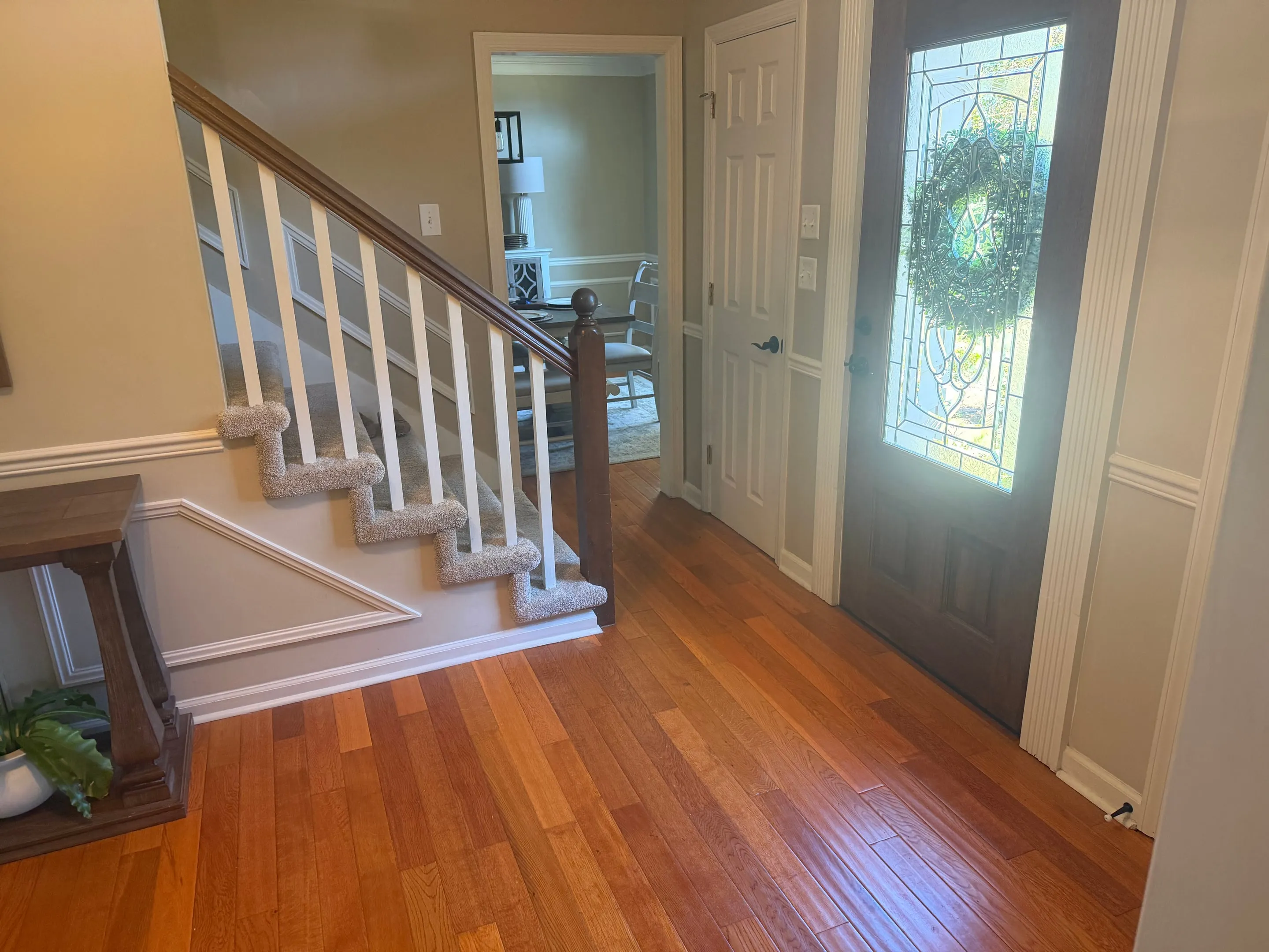 Leaded-glass front door beside a staircase with white balusters and a wood handrail.