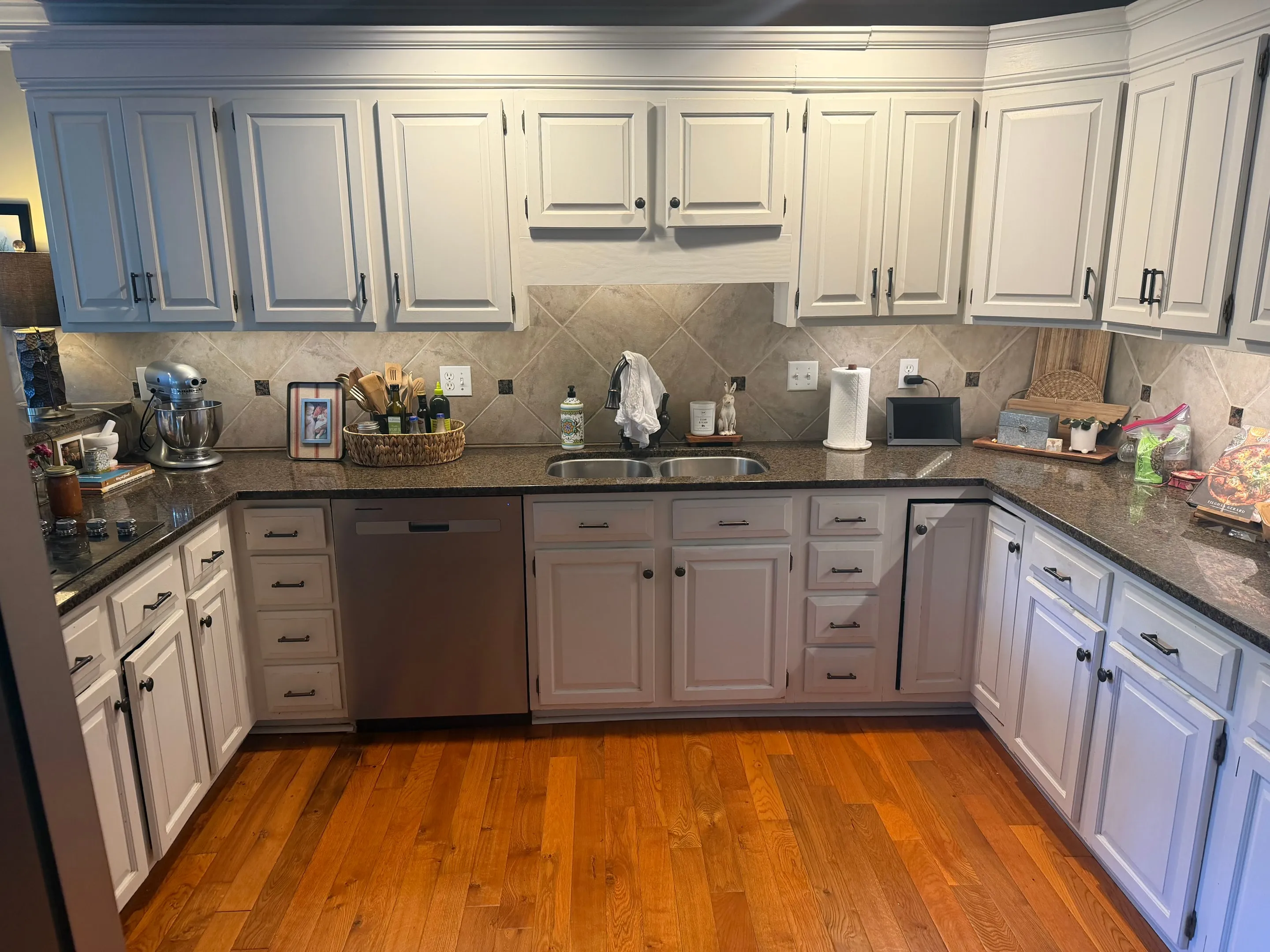 White upper and lower cabinets around a double sink and a stainless dishwasher.