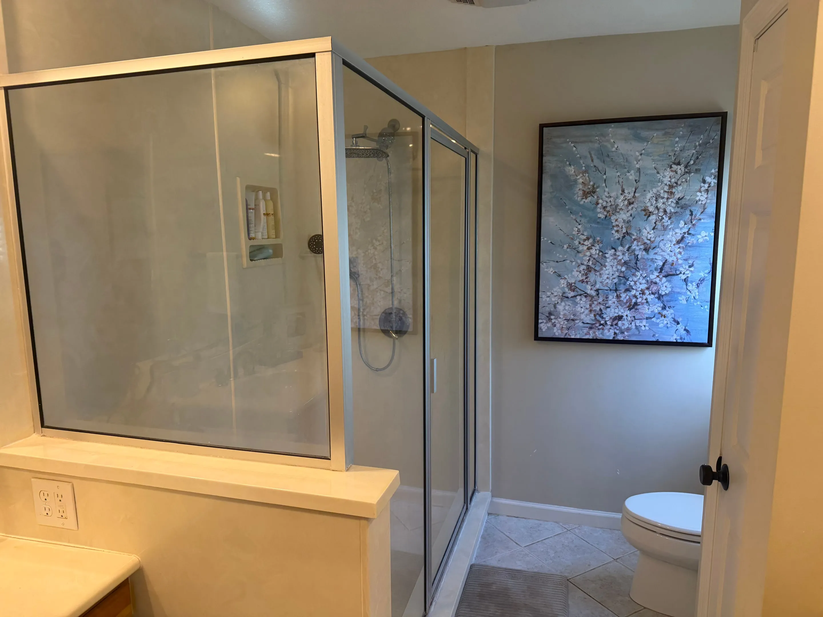 Primary bathroom with a glass-enclosed shower and tile floor.