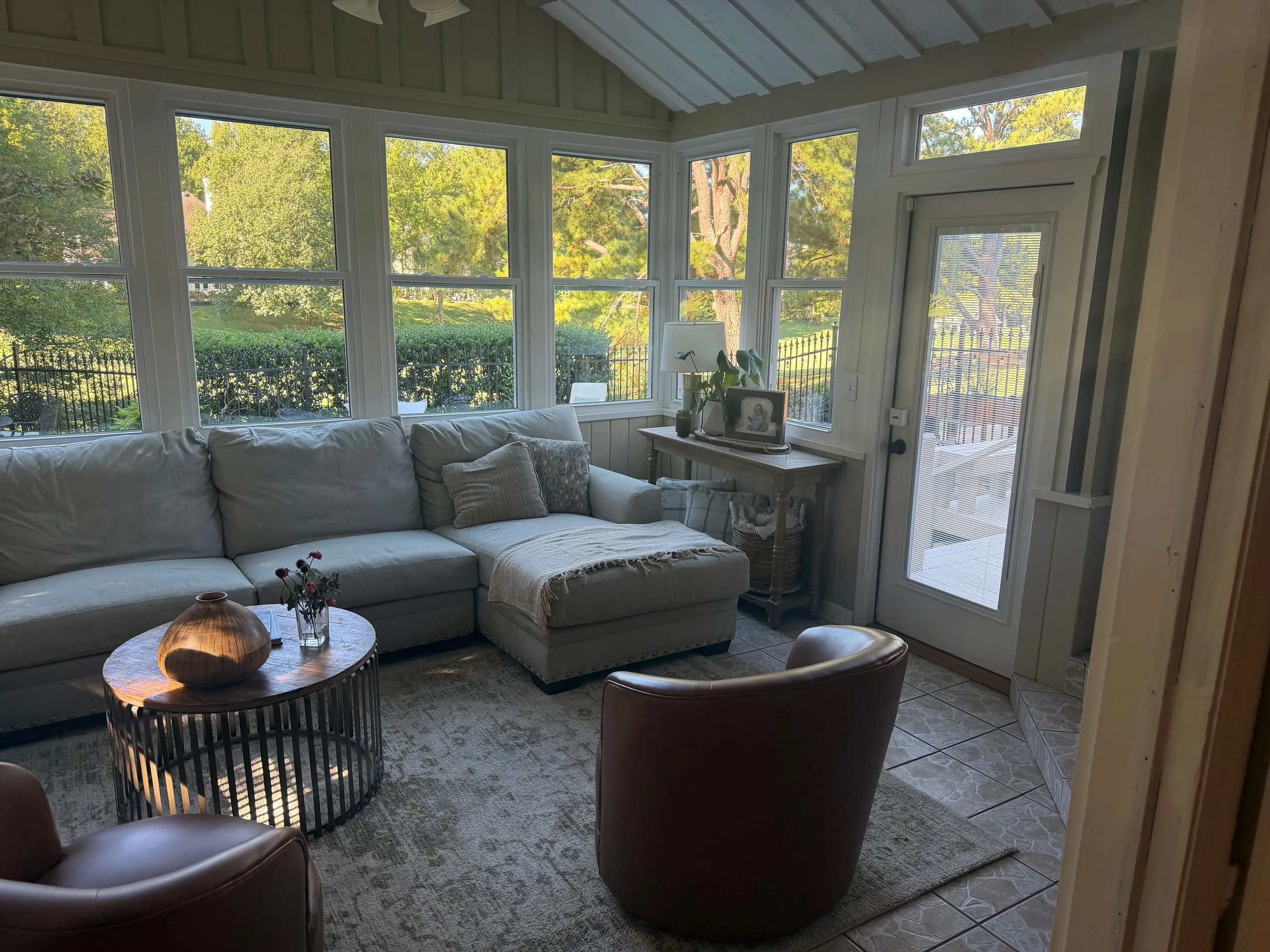 Sunroom with a vaulted ceiling, a wall of windows, and a glass door leading outside.
