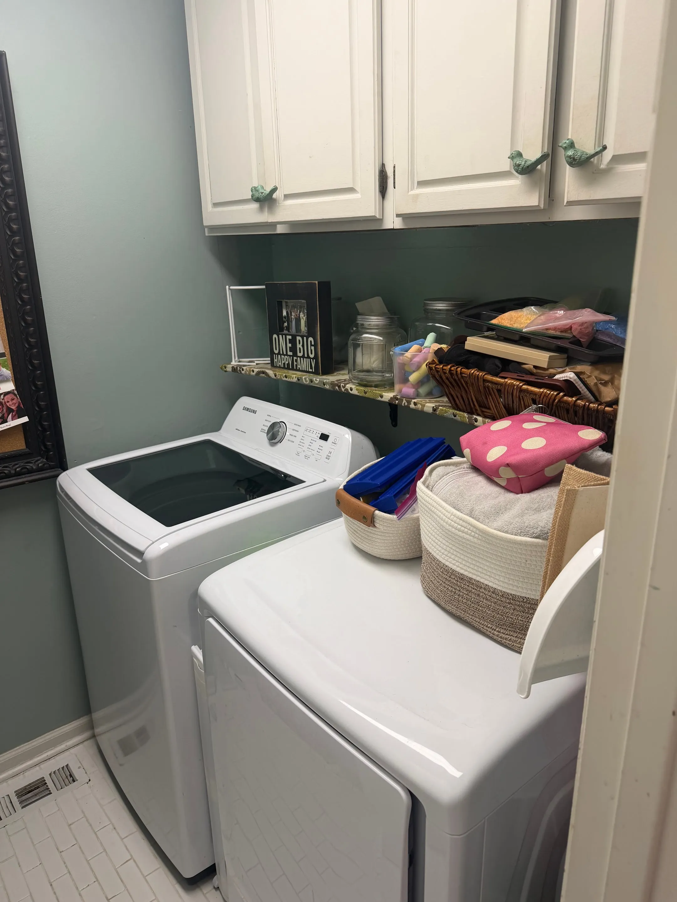 Utility room with a washer and dryer, white upper cabinets, and a tile floor.